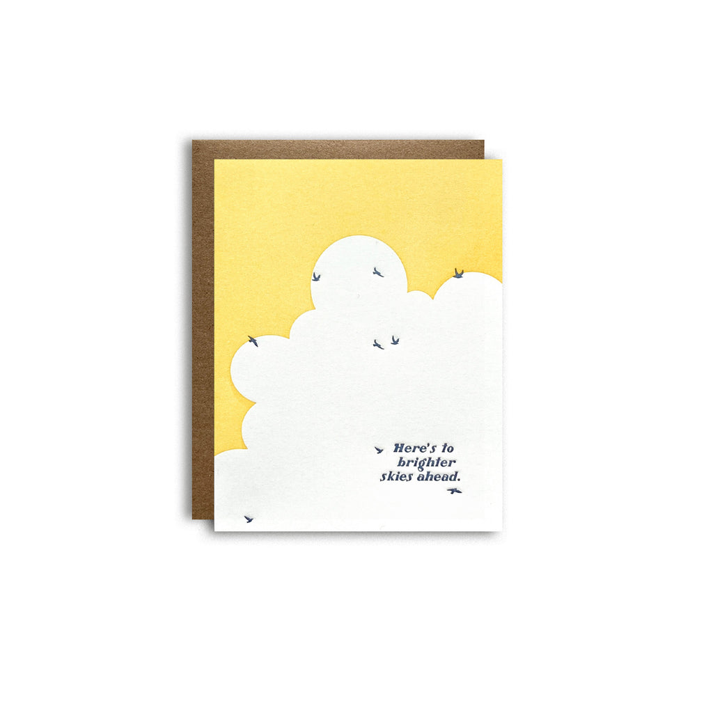 birds flying in sky with words "here's to brighter skies ahead" card featured on a white background shown with a kraft paper envelope
