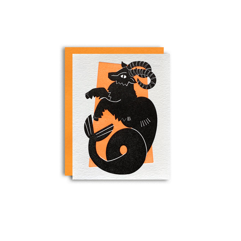 Capricorn zodiac letterpress birthday card. Black letterpress printed sea goat. Neon orange pattern in background symbolizing earth element. Shown with a orange envelope on a white background.